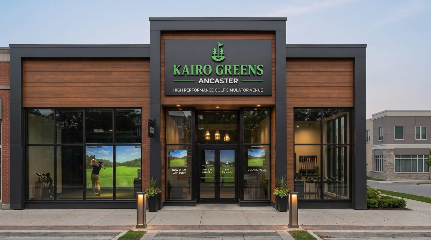 The lit Kairo Greens Ancaster storefront at dusk, a golfer mid-swing visible in a bay through the front window